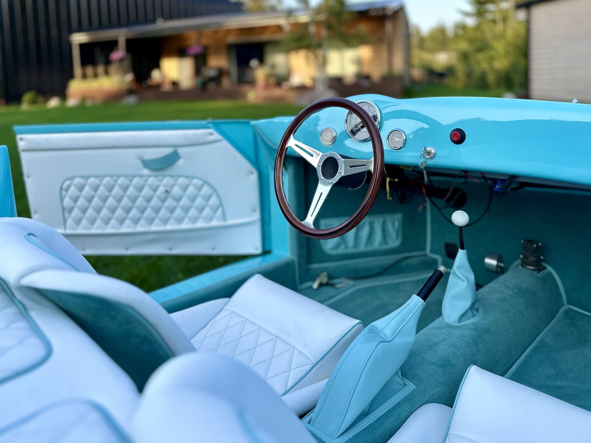 Fresh two-tone upholstery and a wood-rimmed wheel in an open roadster